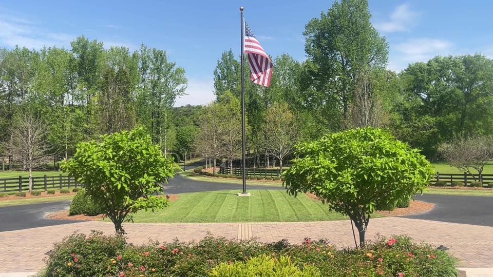 An american flag is flying in front of a lush green field