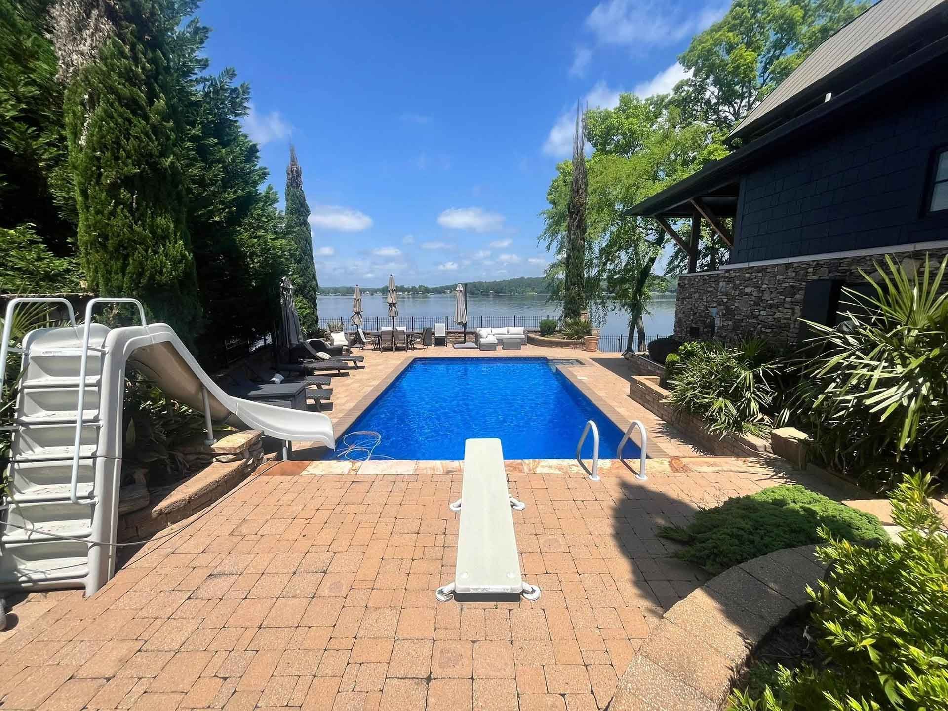 A large swimming pool with a slide in the backyard of a house