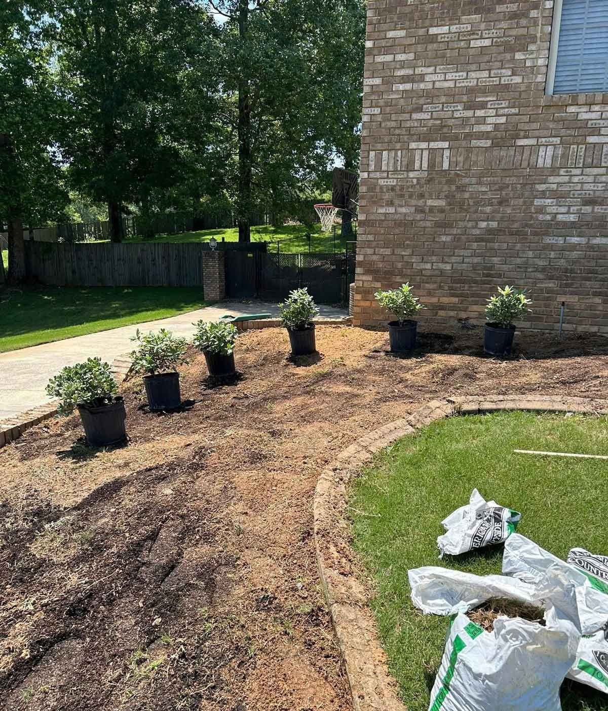 A brick building with a lot of potted plants in front of it.