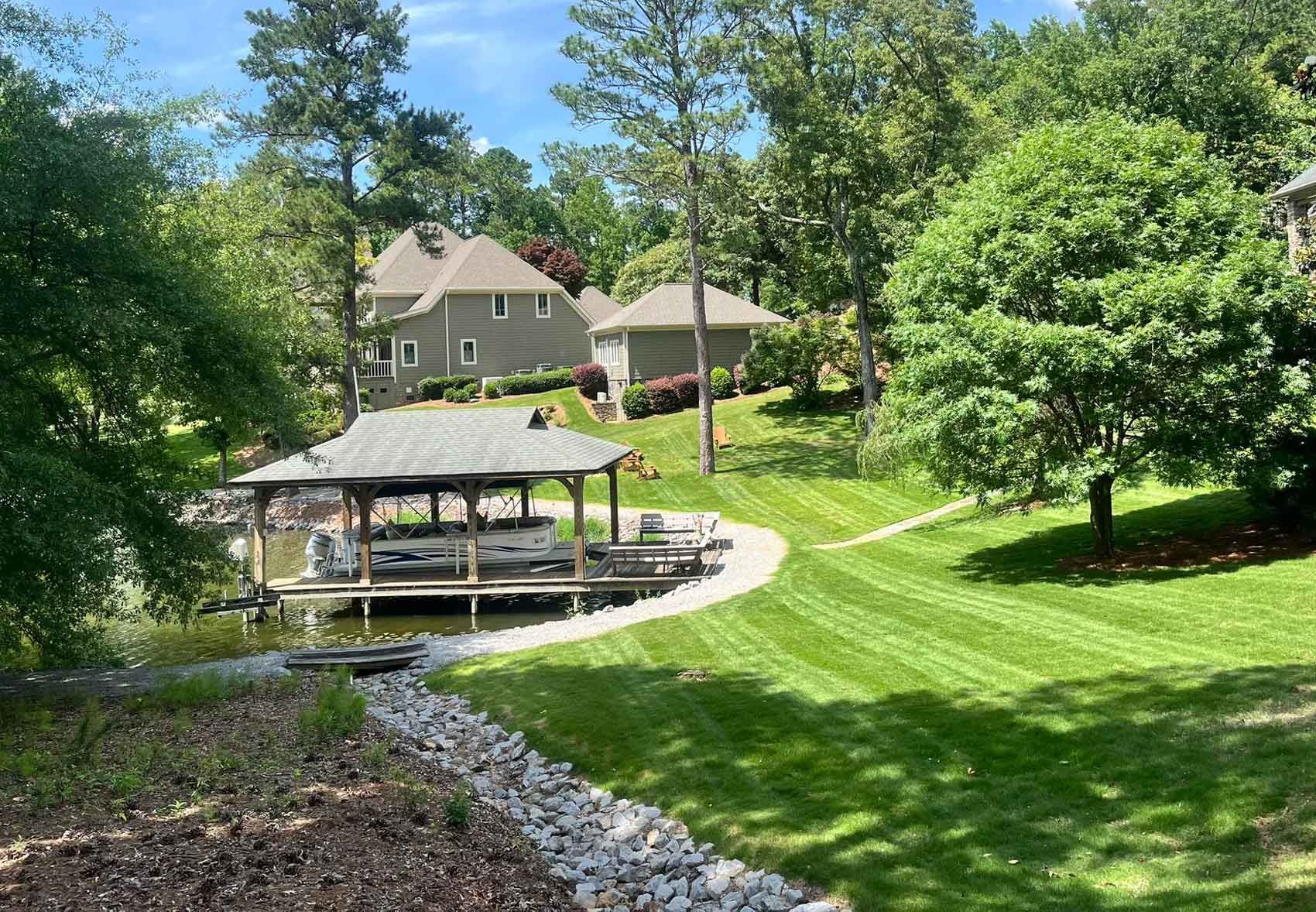 A large lawn with a dock and a house in the background.