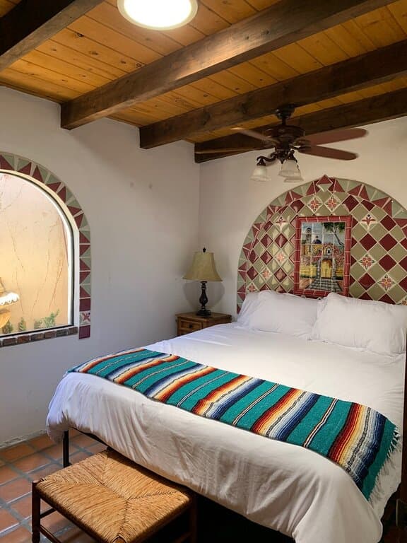 King-size bed, sage green and red wine colored tiles above bed, and curved window with surrounding tile