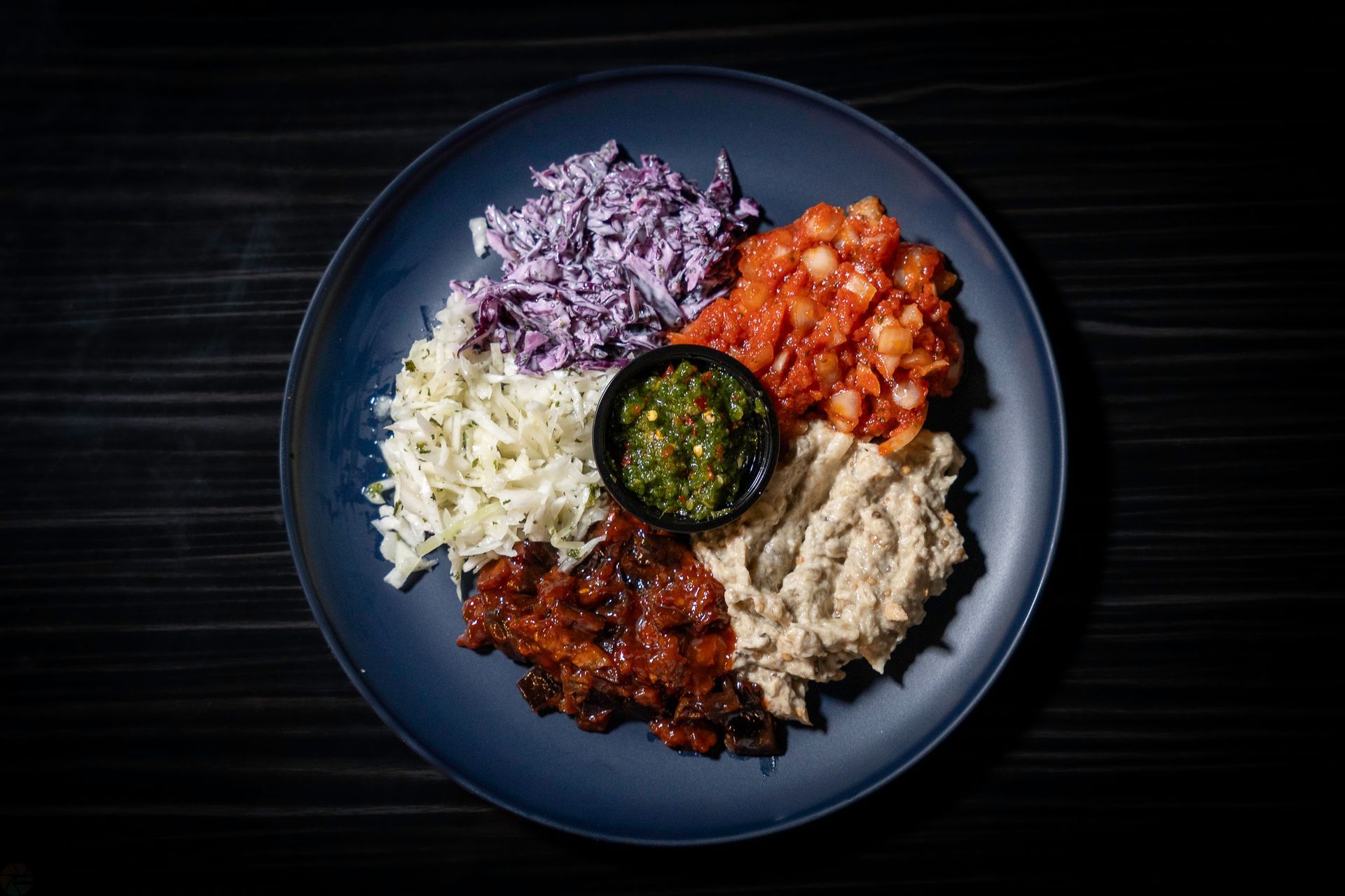 A blue plate topped with different types of food on a wooden table.