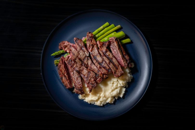 A blue plate topped with steak , mashed potatoes and asparagus.