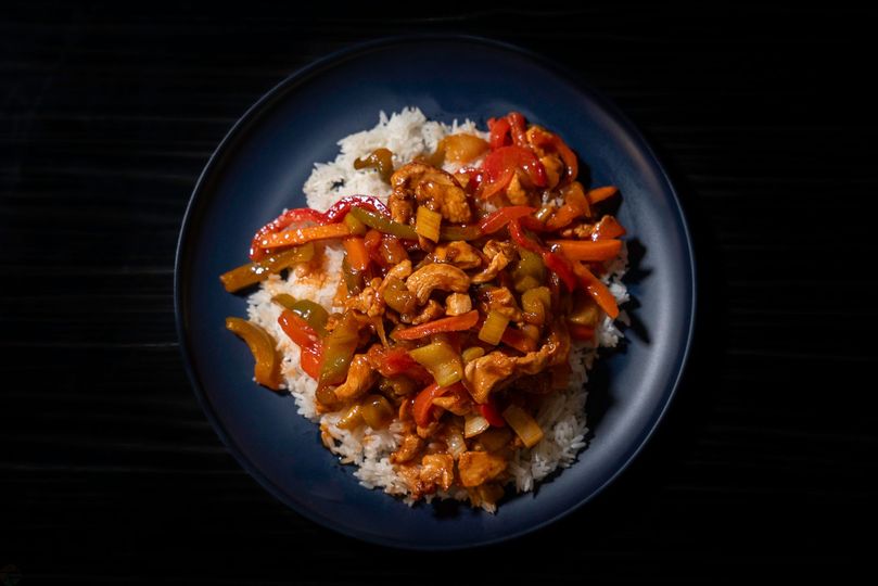 A plate of food with rice and vegetables on a black background.