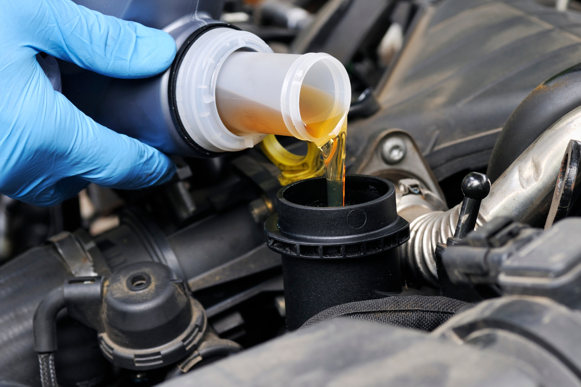 A person is pouring oil into a car engine.
