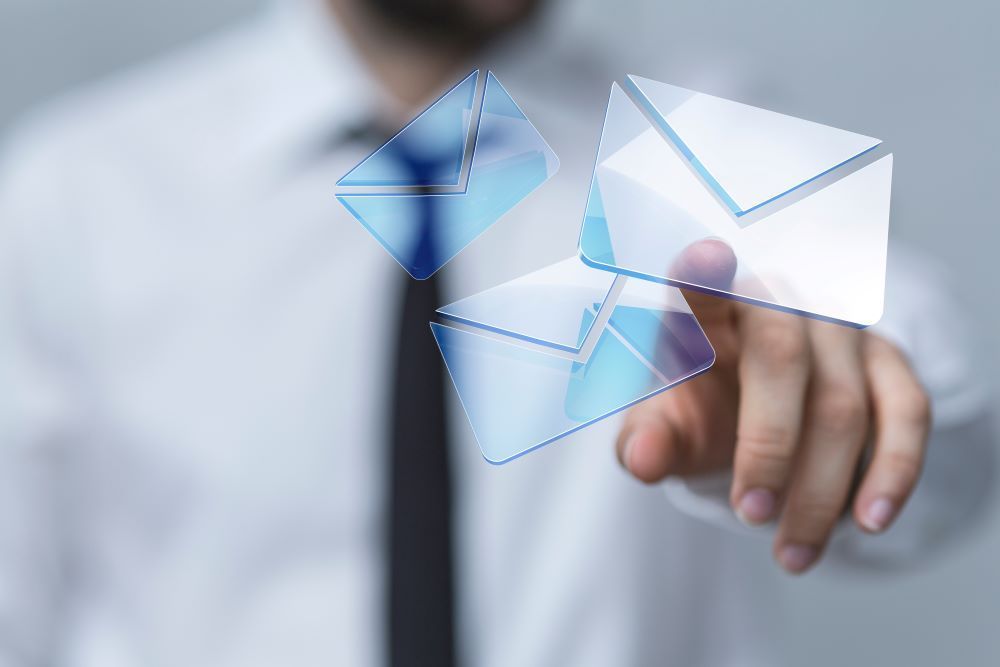 Man pointing at envelopes floating through the air representing emails being sent