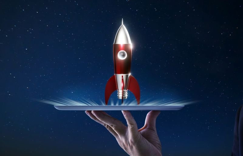 A space rocket launching out of a laptop held in someones hand
