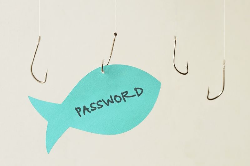 Paper cut-out of a fish with the word 'password' on it, caught by a fish hook representing Phishing