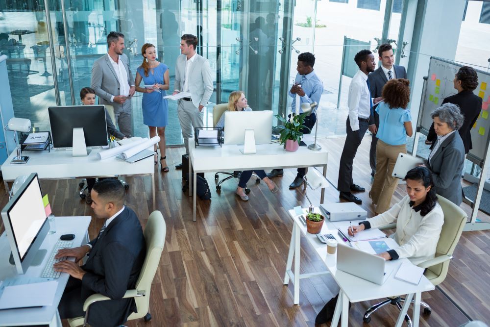 A modern office workspace with people chatting, collaborating and working together