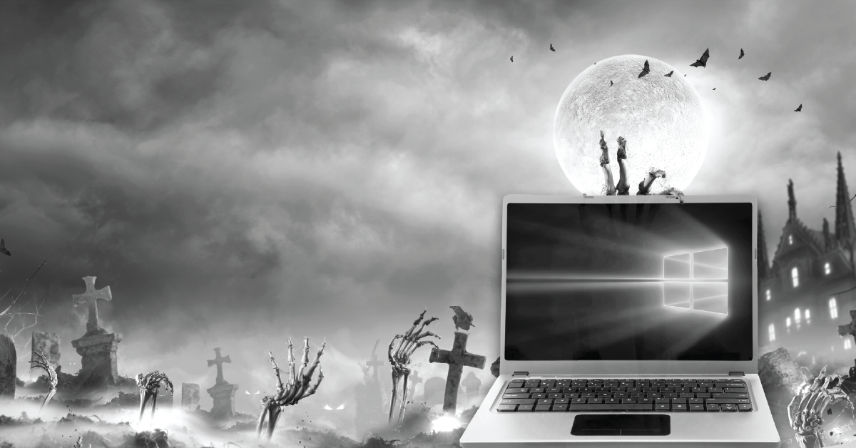 Spooky graveyard scene with bats, skeletons and an open laptop with the Windows icon on the screen