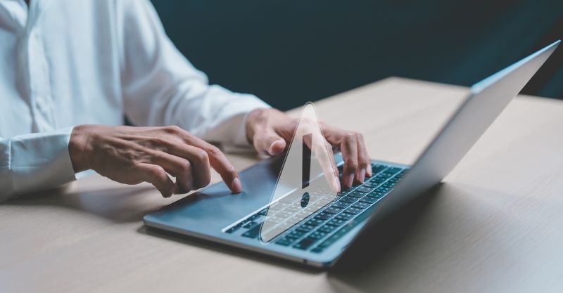 Man trying to use a laptop that is showing a warning symbol