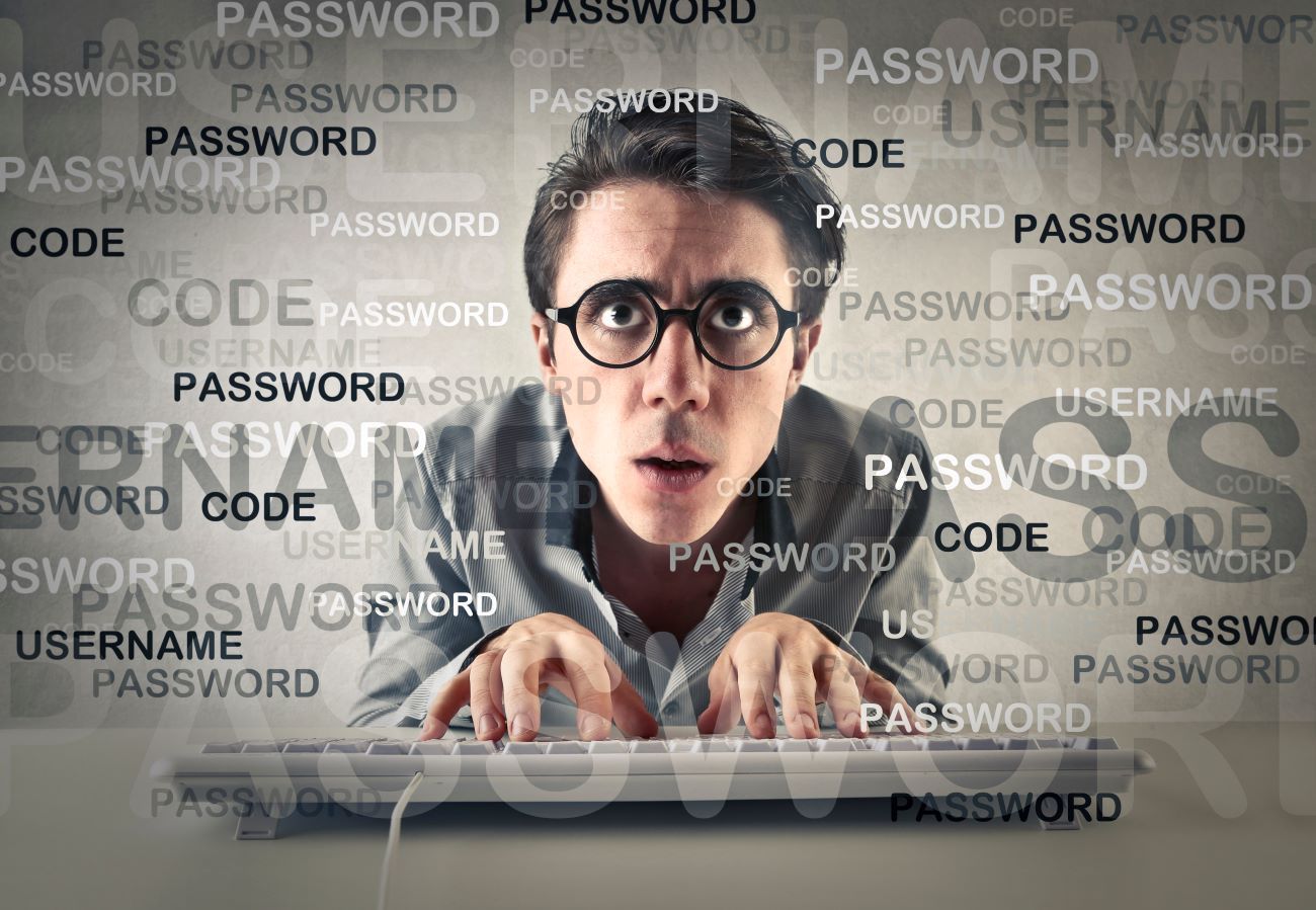 Panicky looking man infront of a computer screen covered in the words 'password' and 'username'