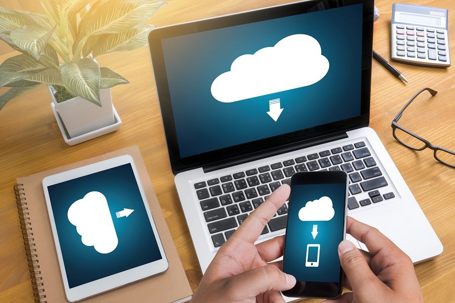 An open laptop, a tablet and a mobile device all showing a cloud computing symbol on their screens