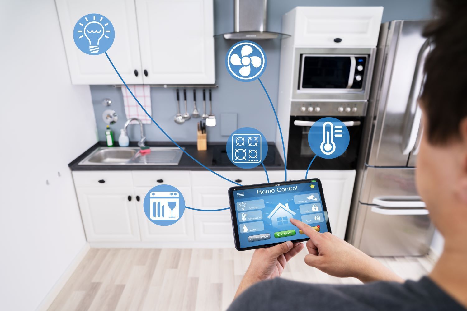 Man holding a smart home controller in his kitchen and turning on lights, fans and dishwasher