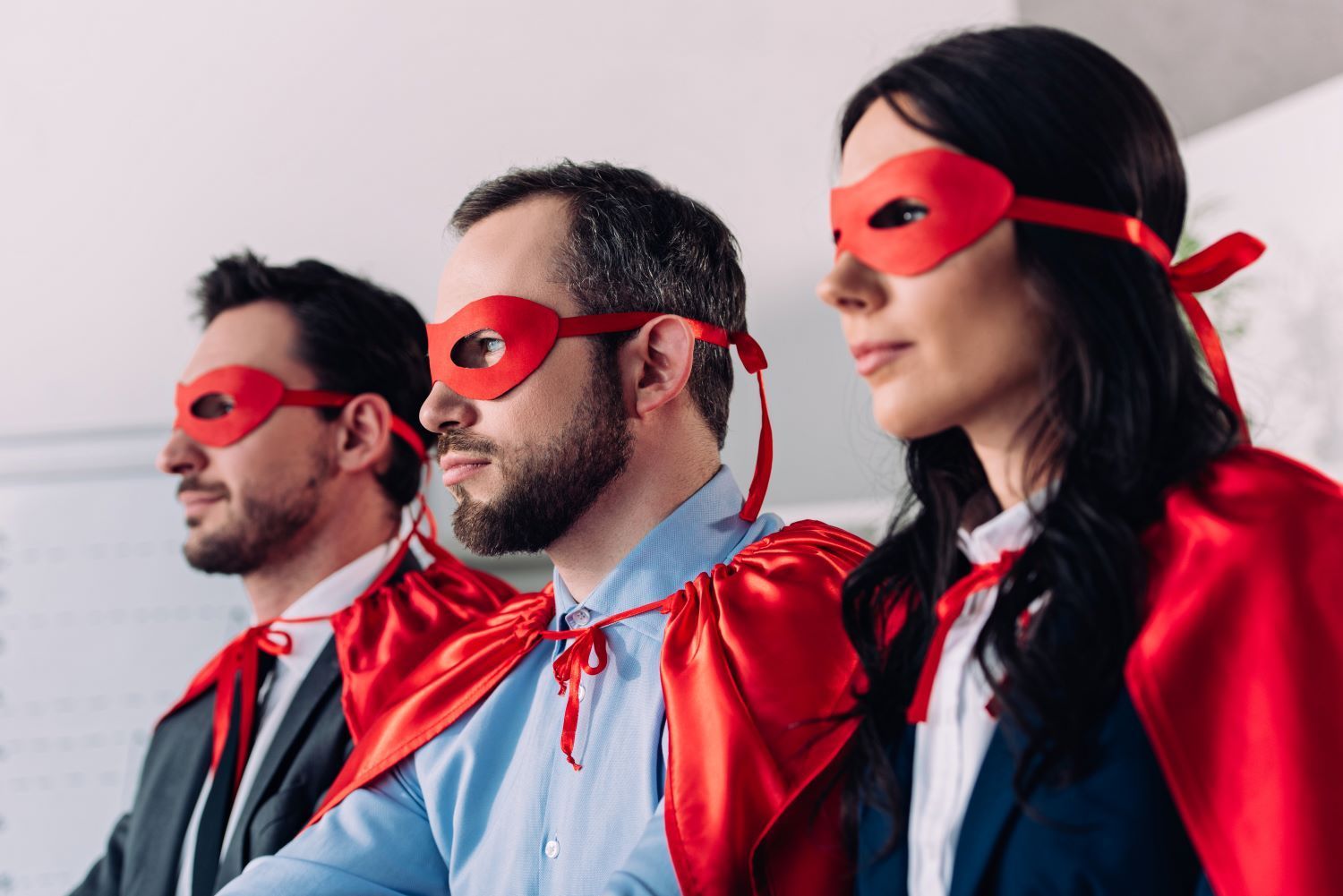 Three people dressed with superhero masks and capes on