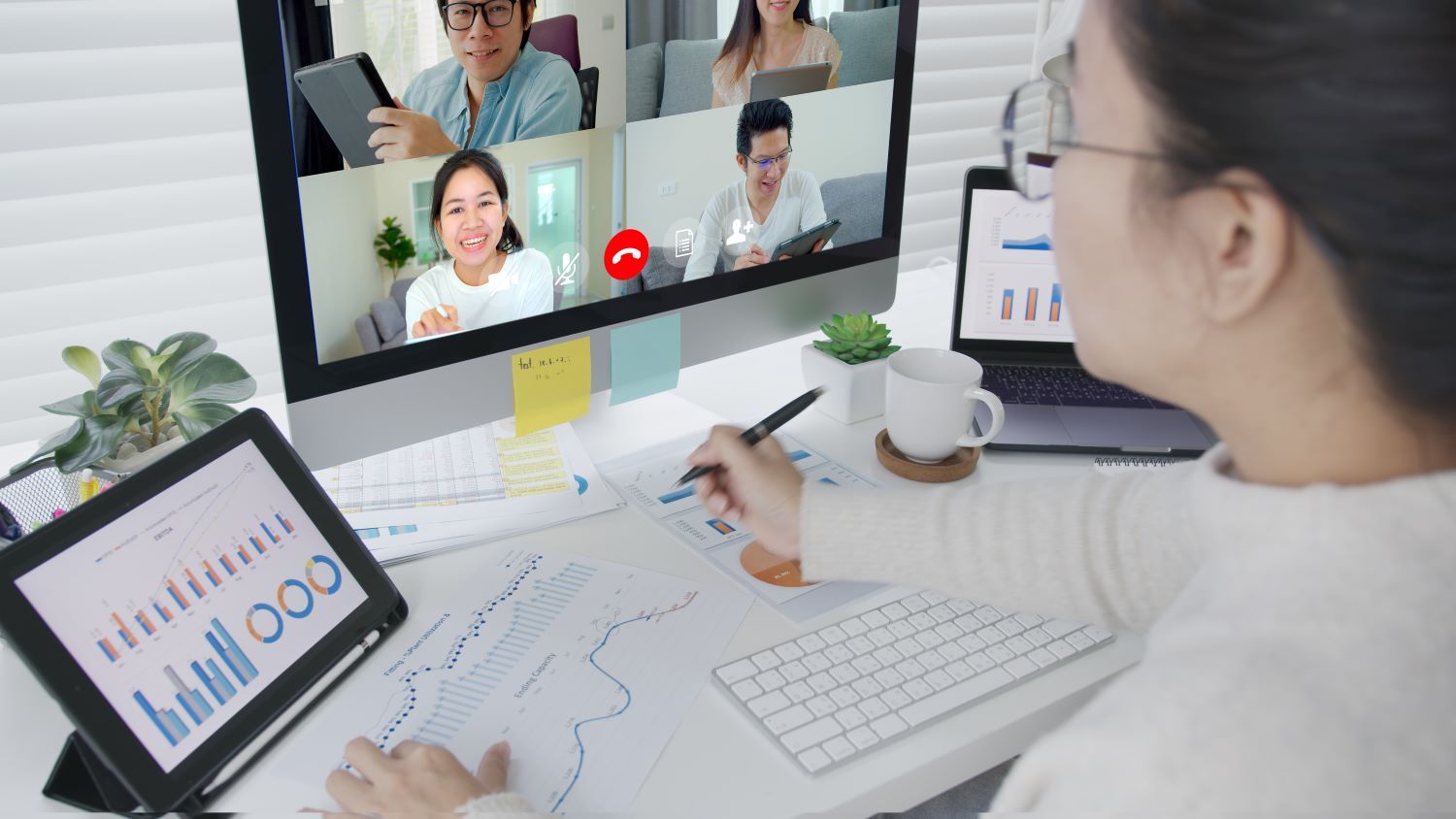 Women working at a desk on a Teams video call with other staff members