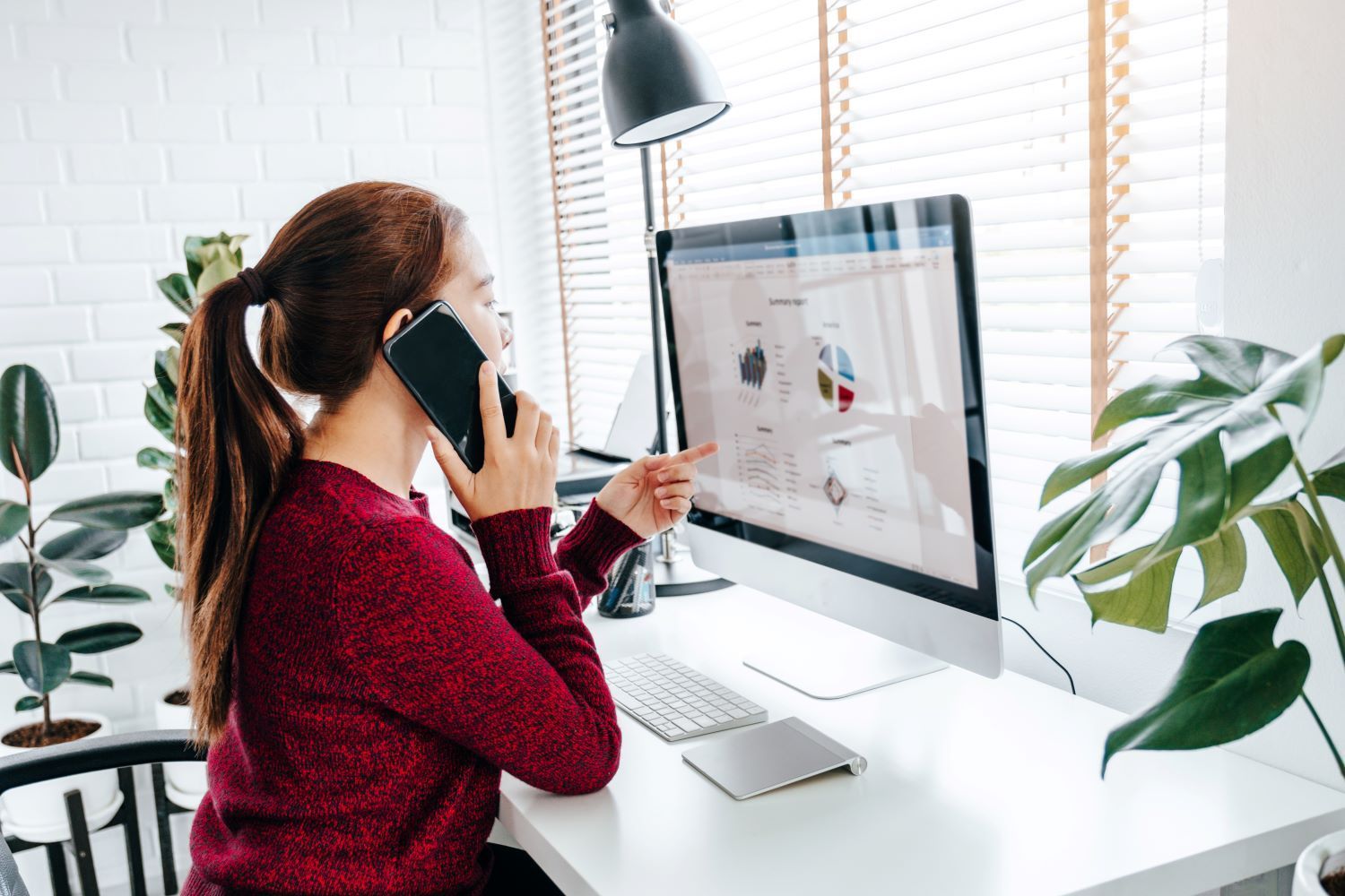 Woman at home working on her computer whilst on a phone call