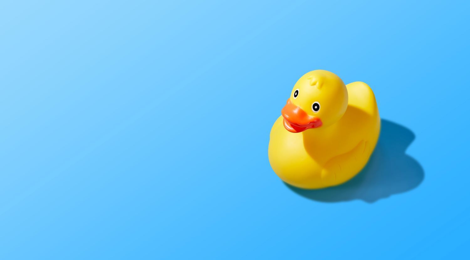 A plastic duck sitting in the middle of a blue floor