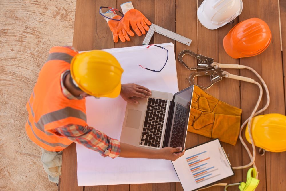 Construction worker in safety helmet looking at a laptop