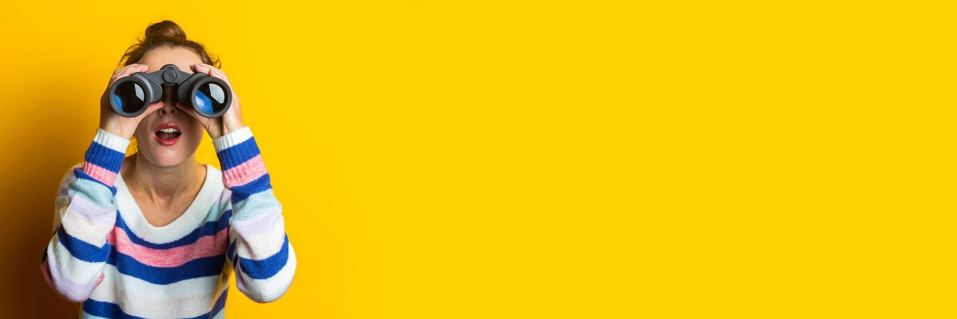 Woman searching for something by looking through a pair of binoculars