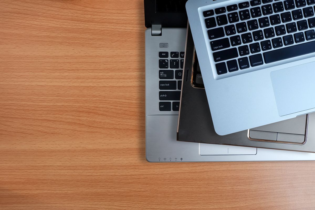 A pile of older laptops on a desk
