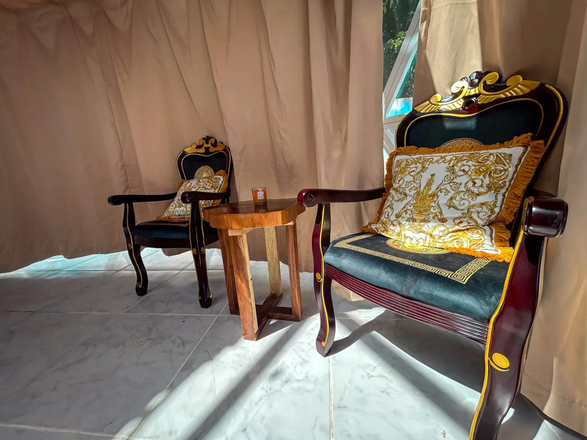 Dos sillones ornamentados con cojines decorativos y una mesita dentro de una tienda de campaña.