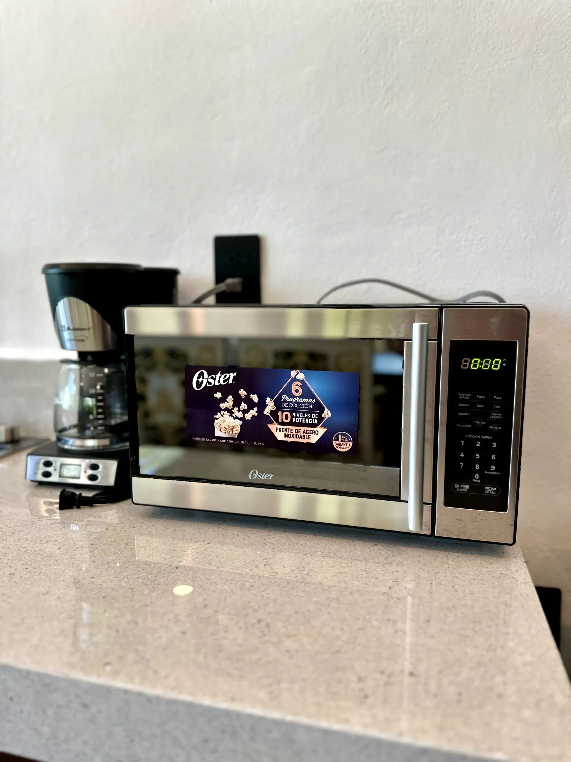 Horno microondas y cafetera sobre la encimera, con una pantalla decorativa visible en la pantalla del microondas.