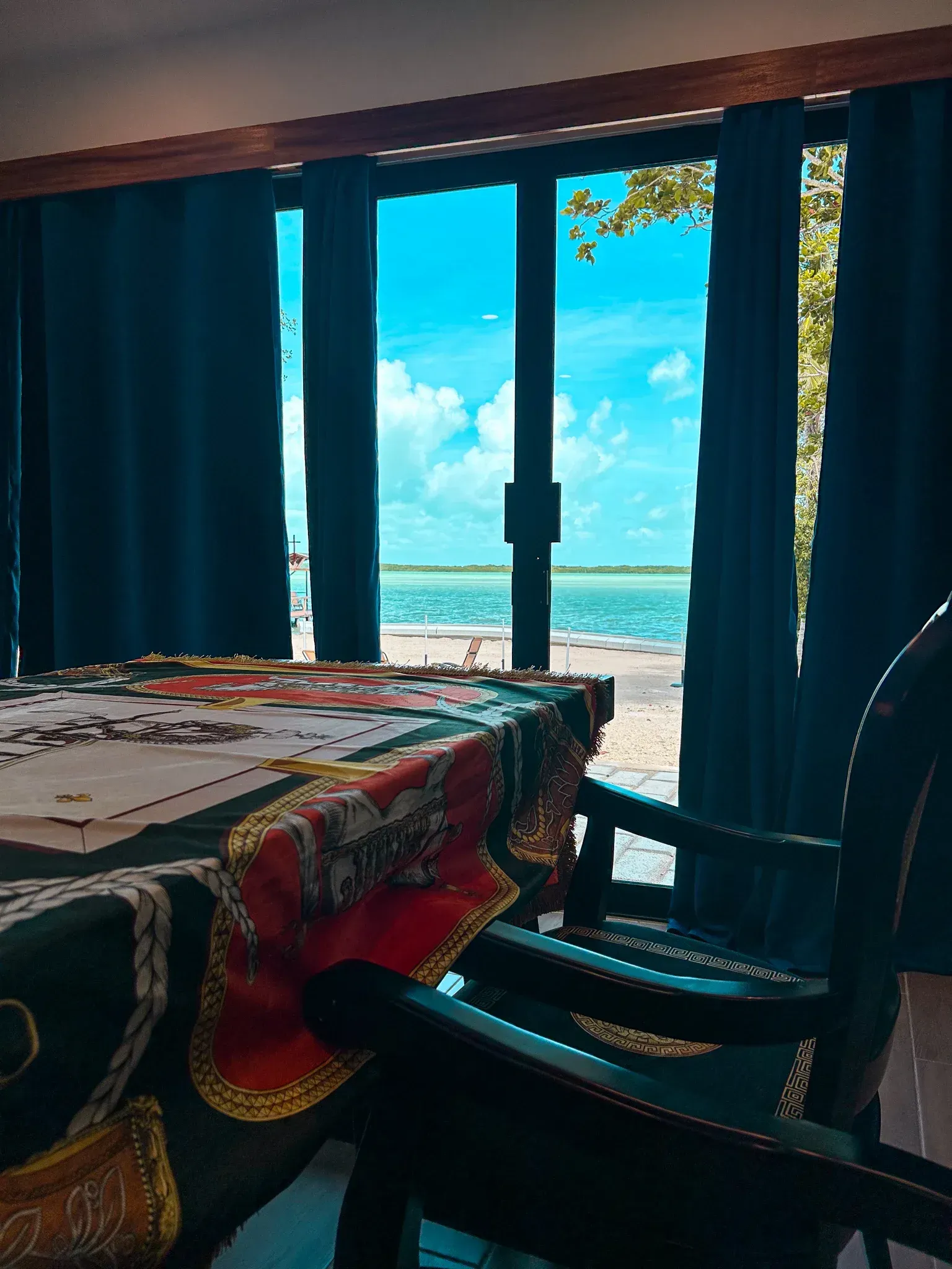 Una mesa dispuesta cerca de una ventana con vistas a un cielo azul brillante y al agua. 