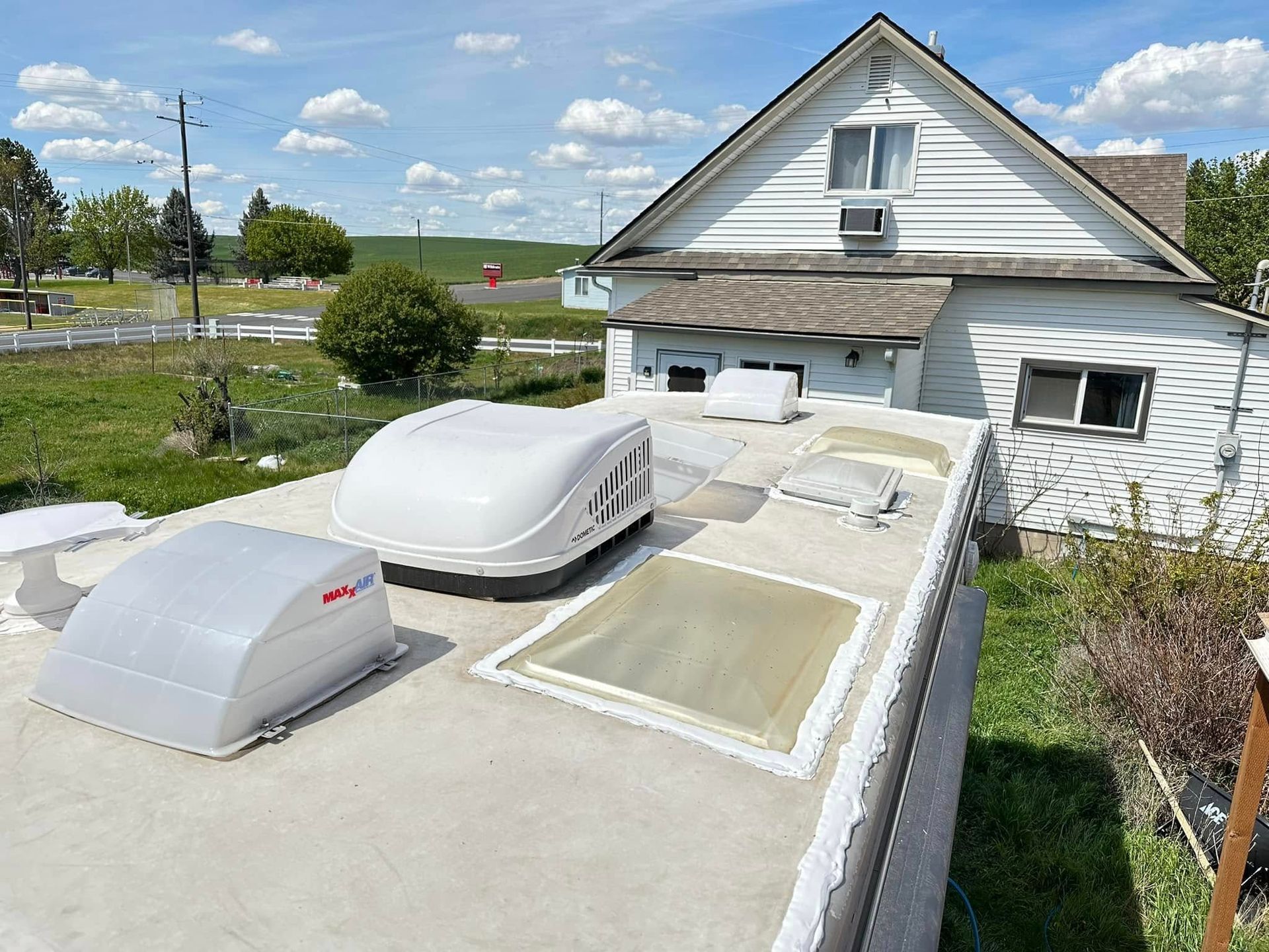 RV roof with vents and skylight; house in the background.