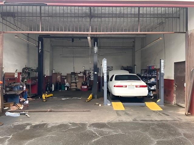 A white car is sitting on a lift in a garage.