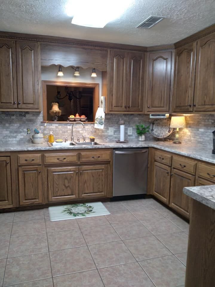 A kitchen with wooden cabinets , granite counter tops , a sink , and a stainless steel dishwasher.