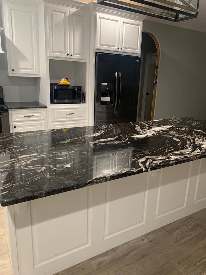 A kitchen with black granite counter tops and white cabinets.