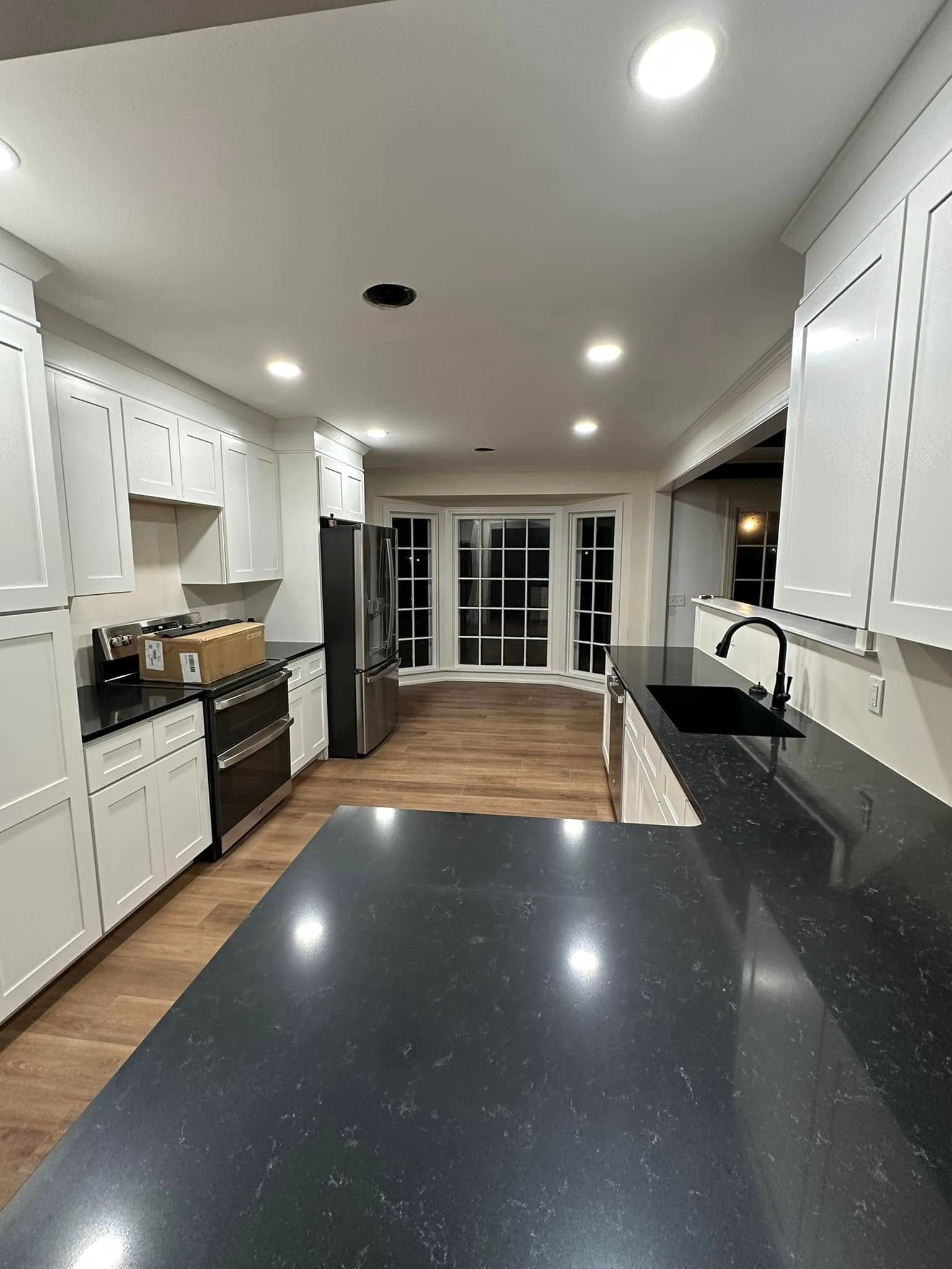 A kitchen with black counter tops and white cabinets