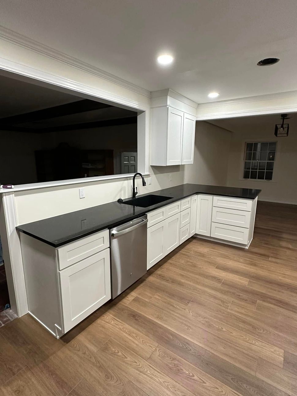 A kitchen with white cabinets , black counter tops , and stainless steel appliances.