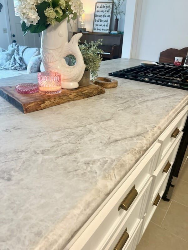 A kitchen counter with a vase of flowers and a candle on it
