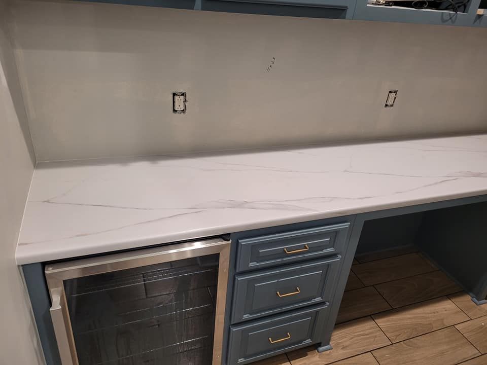 A kitchen with a marble counter top and a stainless steel refrigerator.