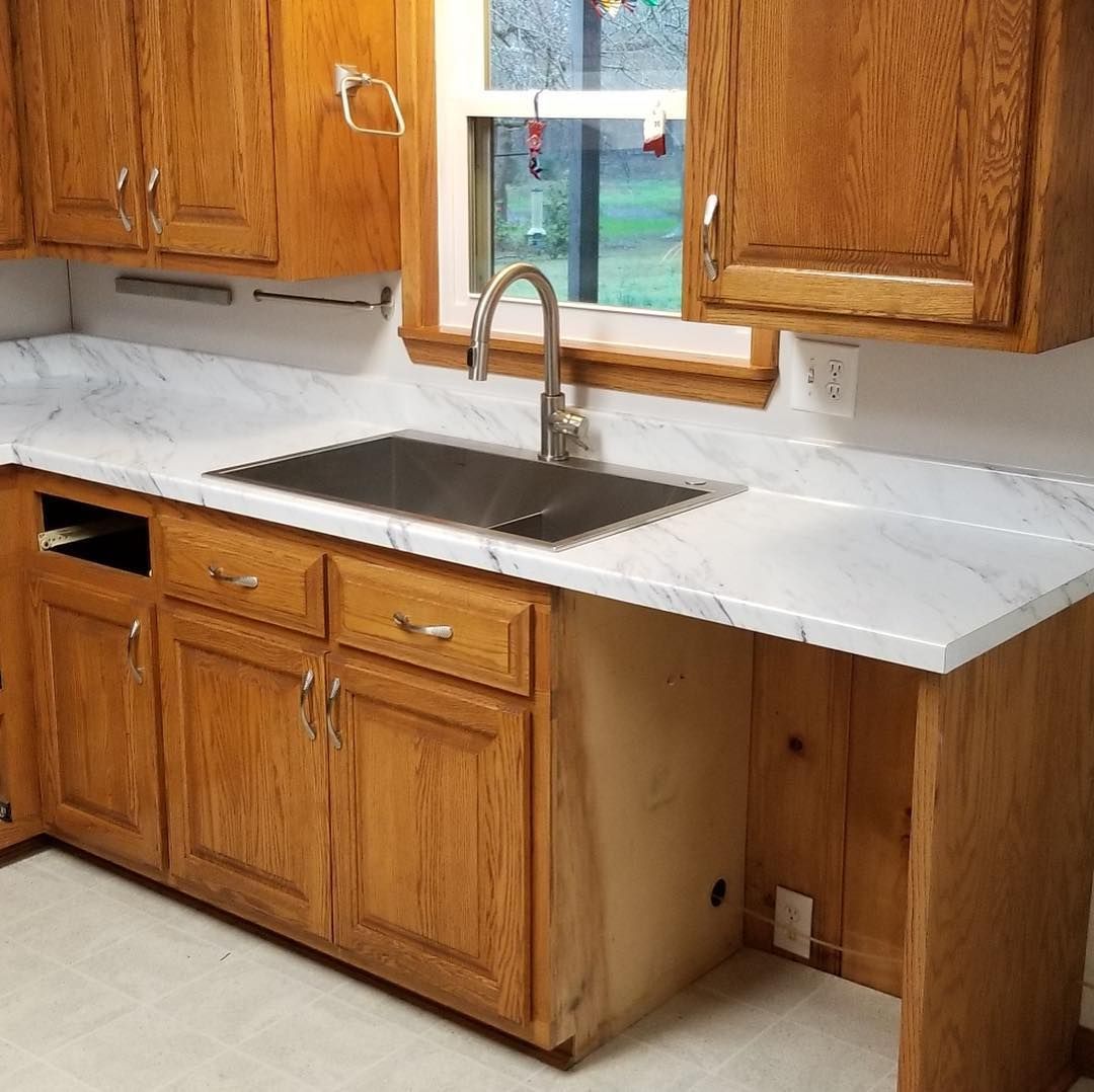 A kitchen with granite counter tops , black cabinets and stainless steel appliances.