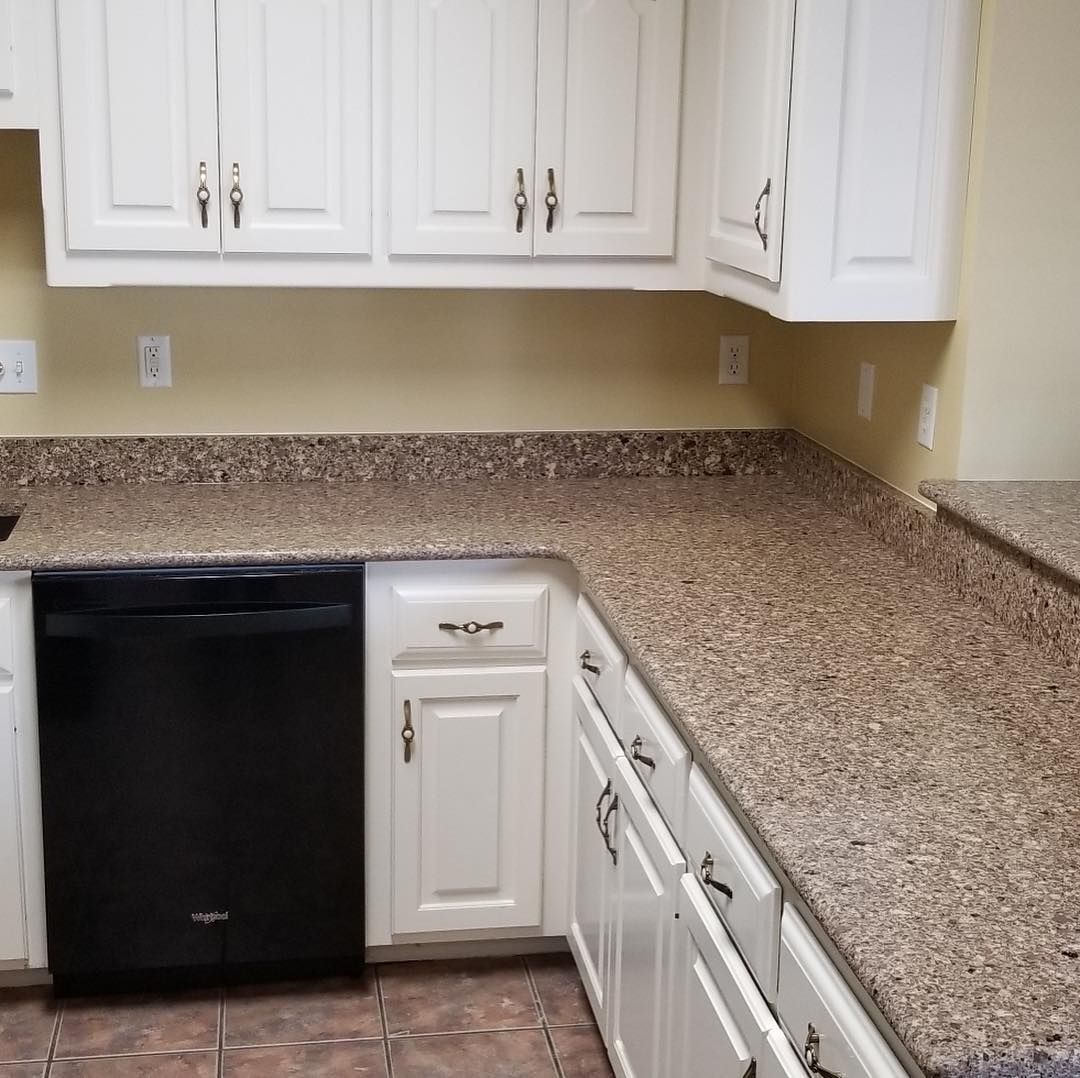 A kitchen with granite counter tops and white cabinets