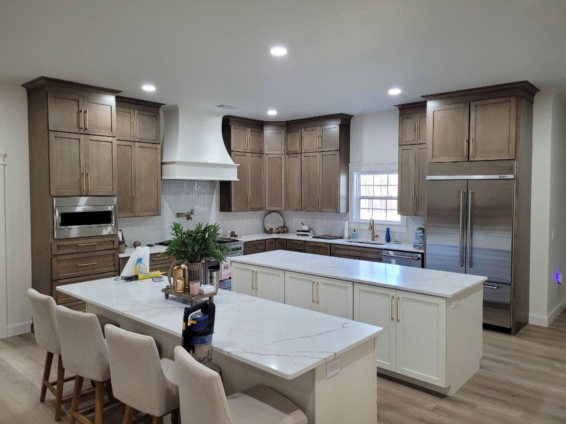 A kitchen with wooden cabinets, white Quartz countertops, stainless steel appliances, and a large island.