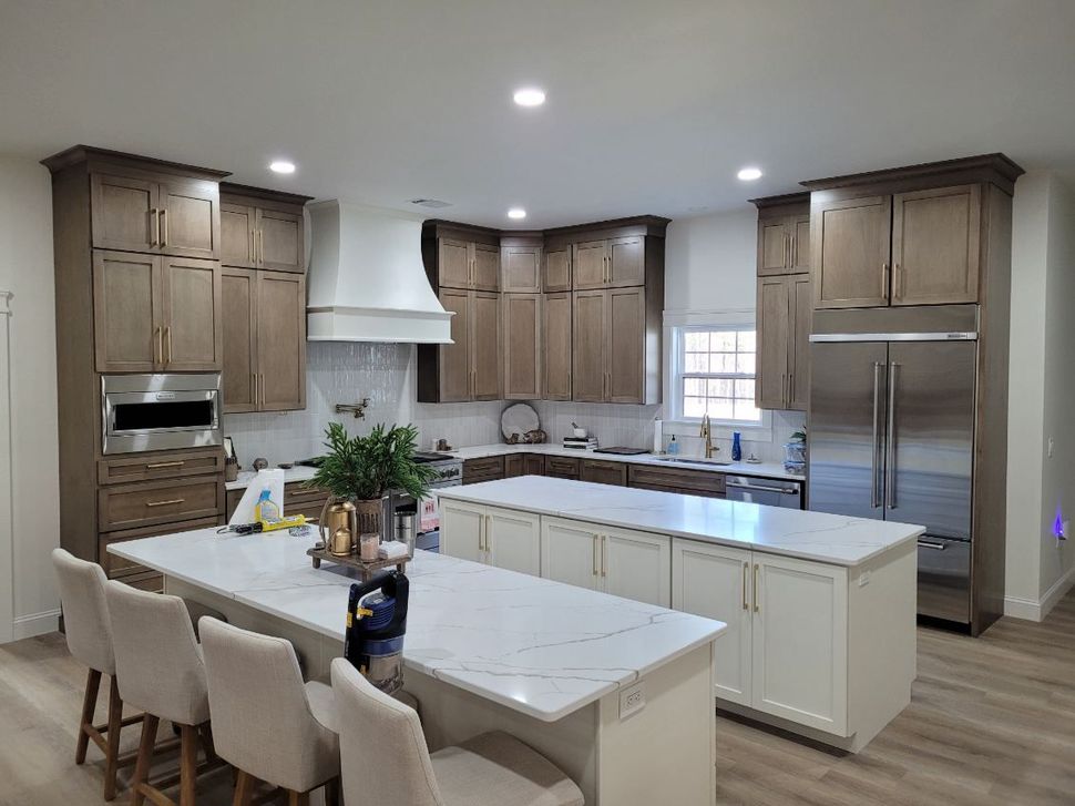 A kitchen with wooden cabinets , white counter tops , stainless steel appliances and a large island.