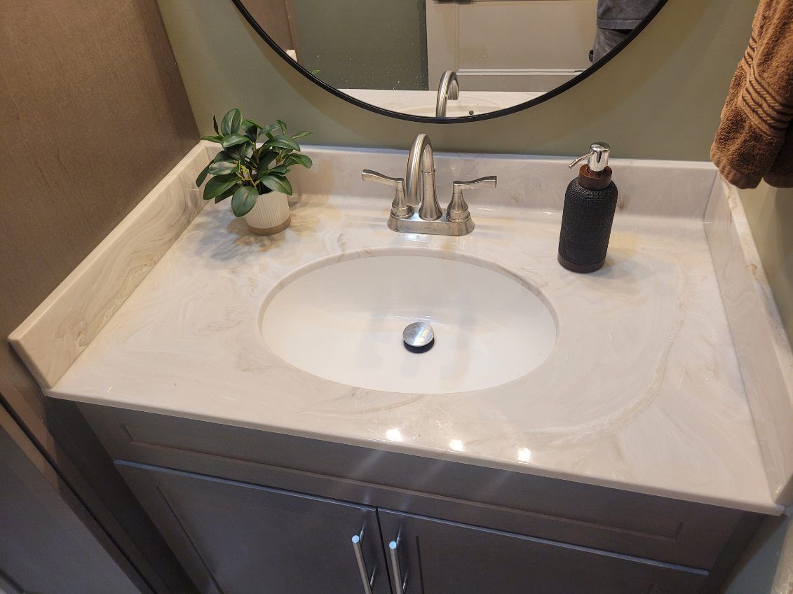 A bathroom sink with a round mirror above it