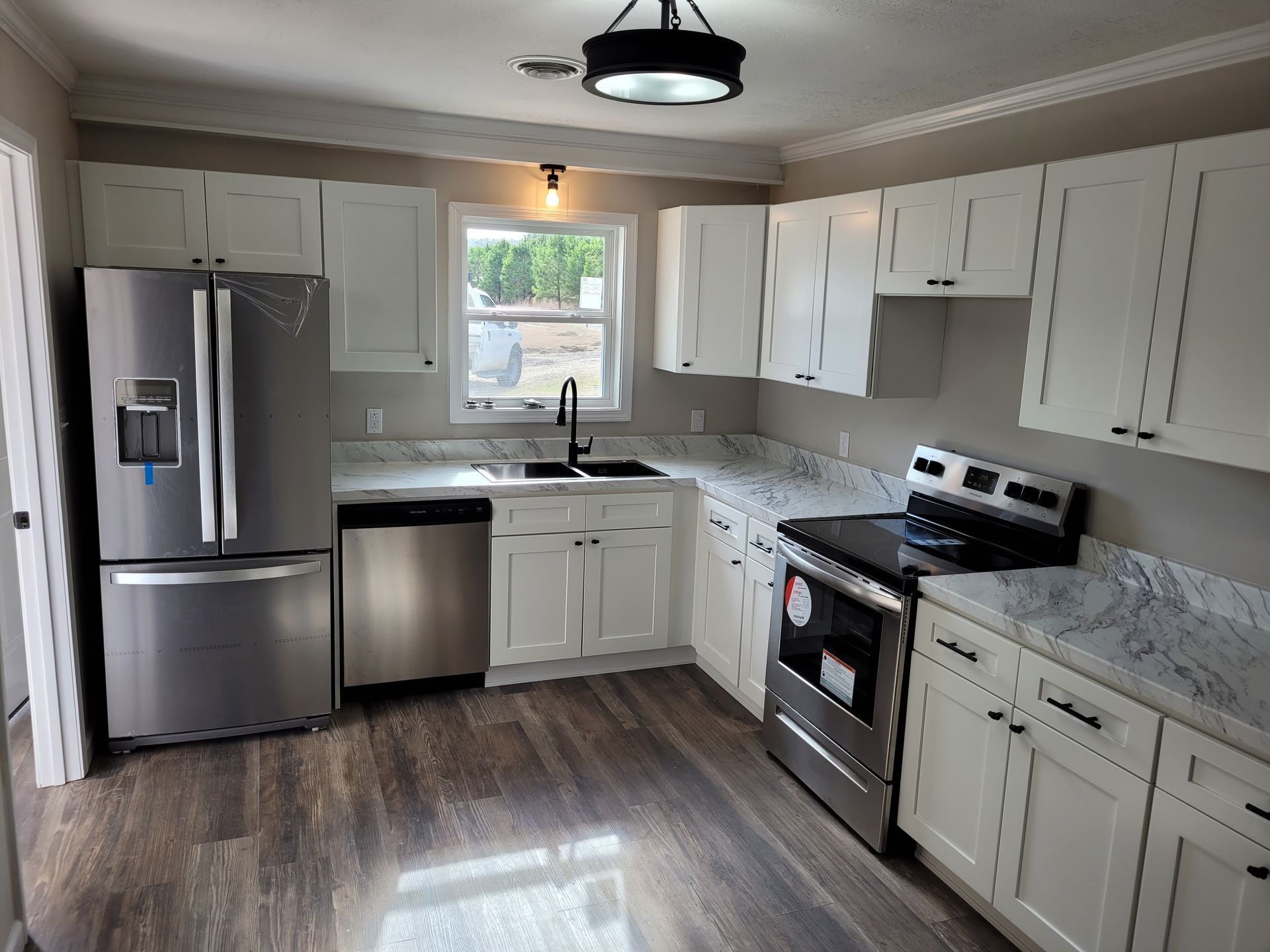 A kitchen with Laminate Calcutta Marble, white cabinets, and stainless steel appliances.