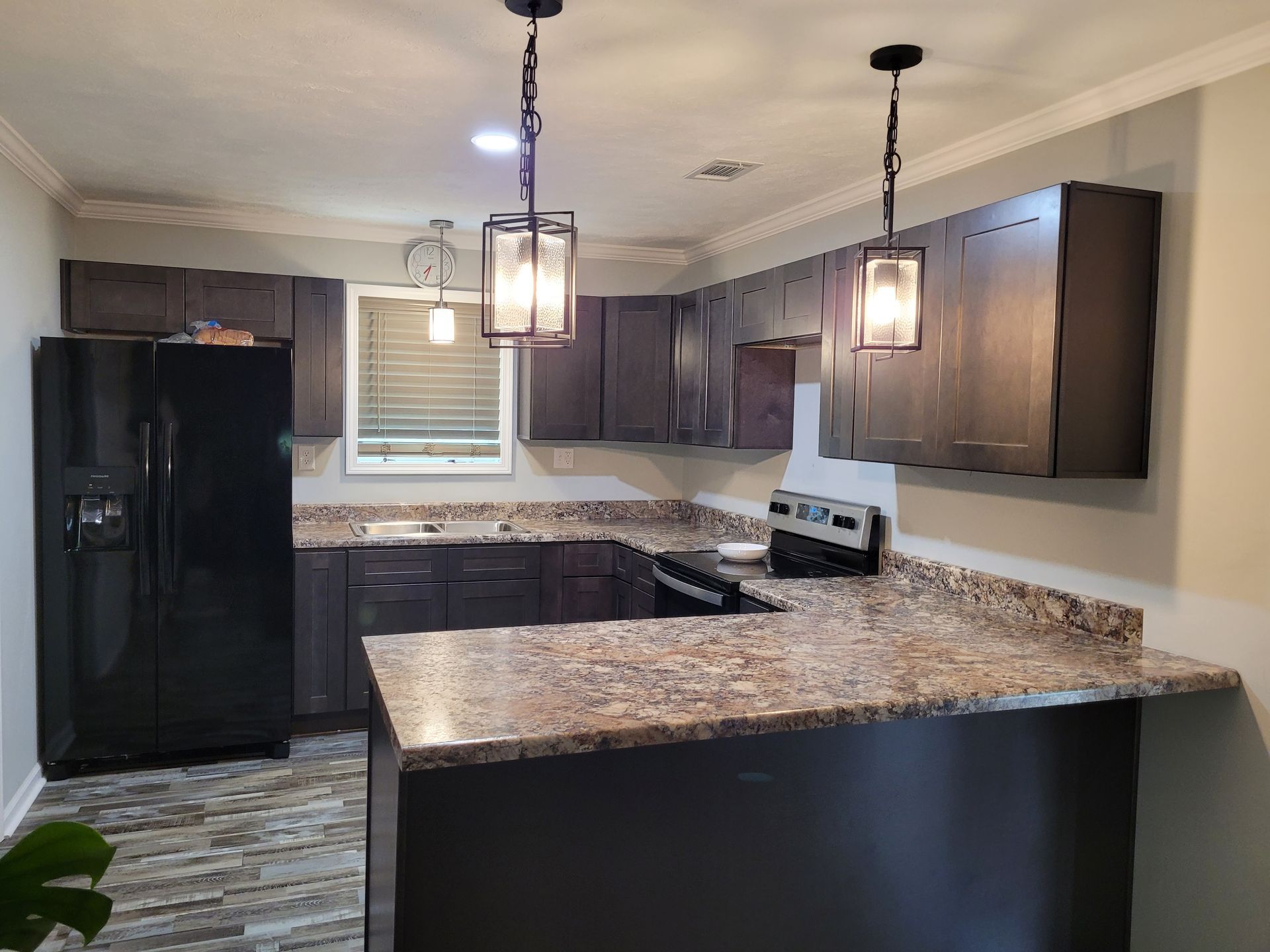 A kitchen with granite countertops and a black refrigerator.