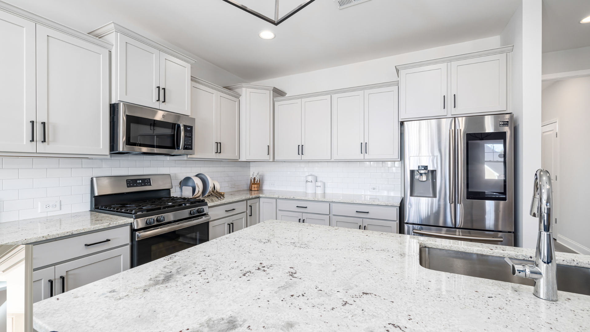 A kitchen with white cabinets , stainless steel appliances , and granite counter tops.