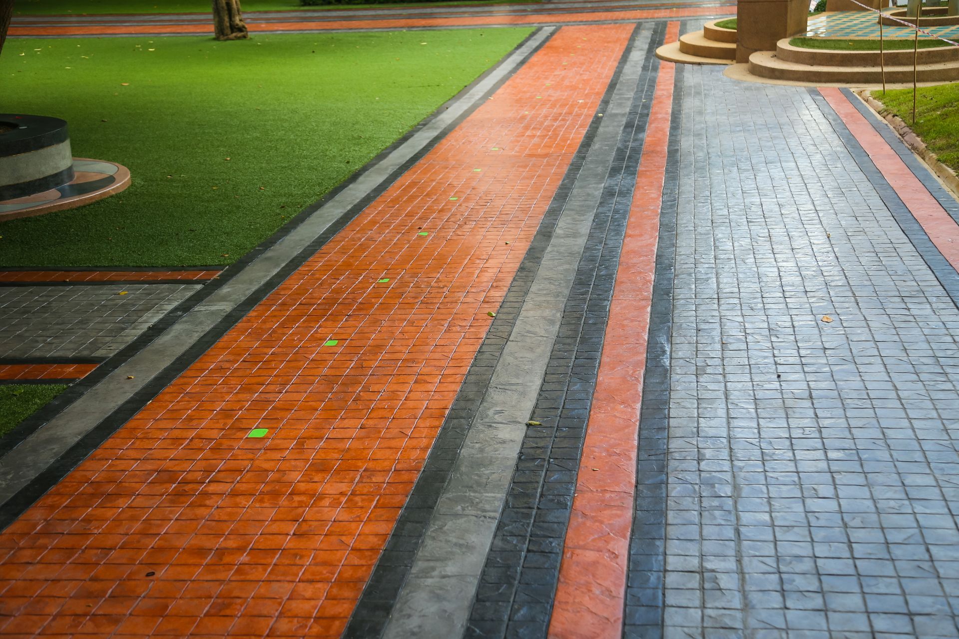 A brick walkway in a park with a grassy area in the background.