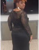 Woman in black dress, turned over shoulder, wearing large earrings.