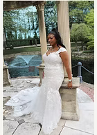 Woman in white wedding dress posing outdoors near a fountain.