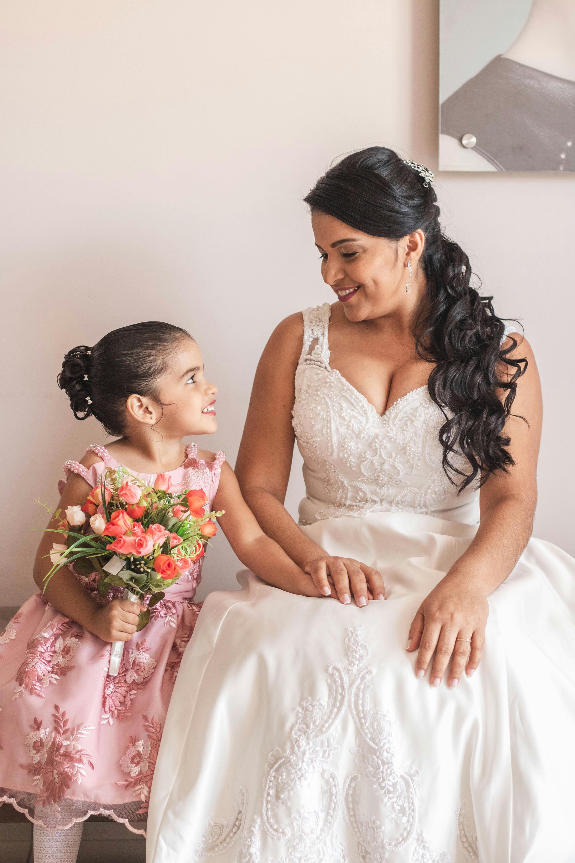 Girl in white dress and floral crown, holding a bouquet, sitting on wooden steps.