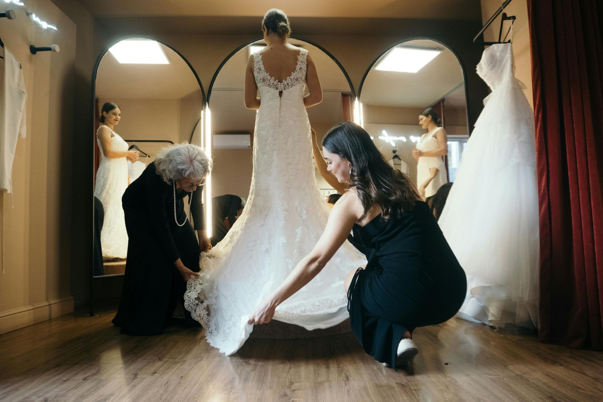 Woman in white lace wedding dress, back view, being buttoned up by someone.