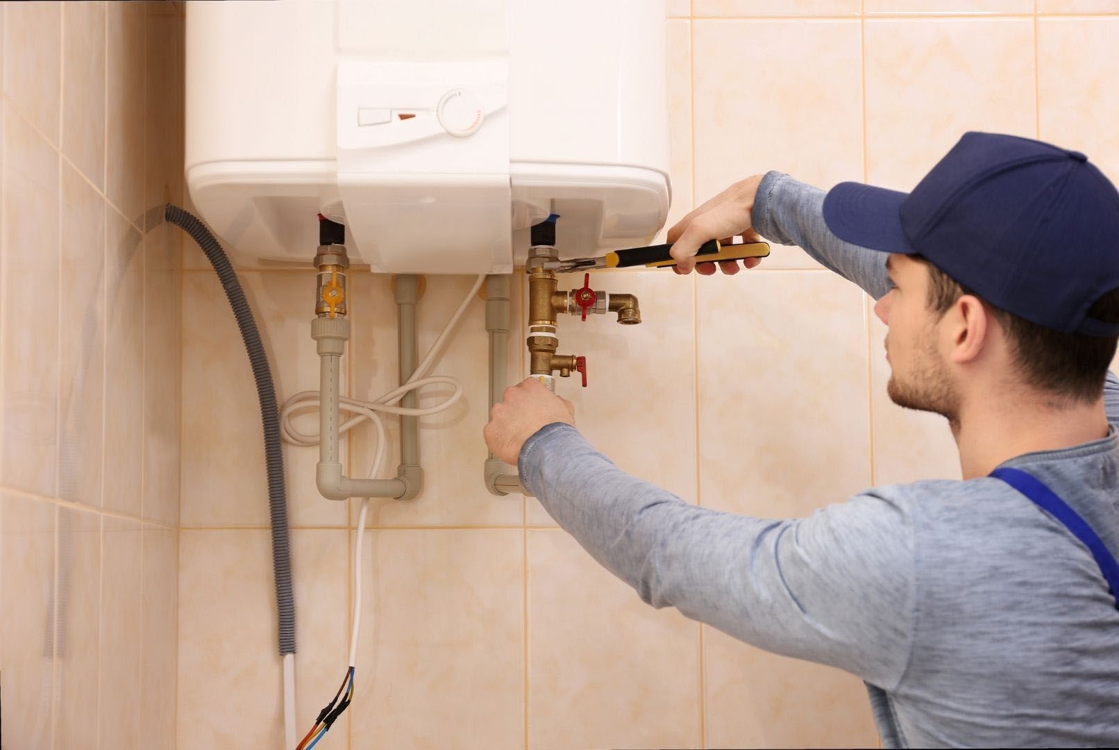 A man is fixing a water heater in a bathroom.
